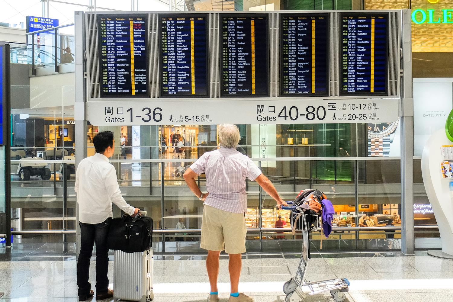 People looking at a departures sign at an airport